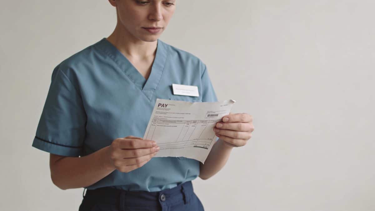Aide soignante en uniforme examinant bulletin de paie