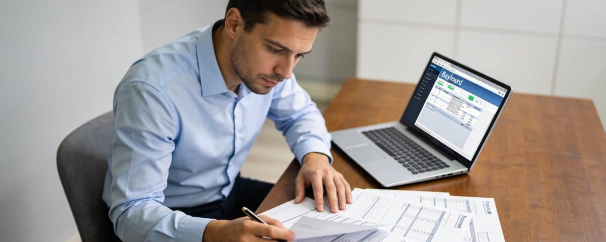 comptable assis devant ordinateur examinant fiches de paie