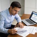 comptable assis devant ordinateur examinant fiches de paie