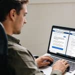 Entrepreneur assis devant ordinateur comparant deux sites internet