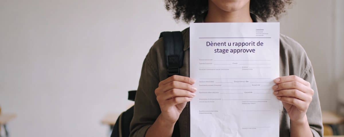 etudiante souriante tenant un rapport de stage approuve