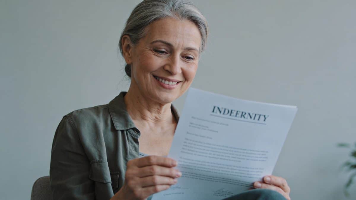 Femme de 55 ans souriante consultant une lettre d indemnisation