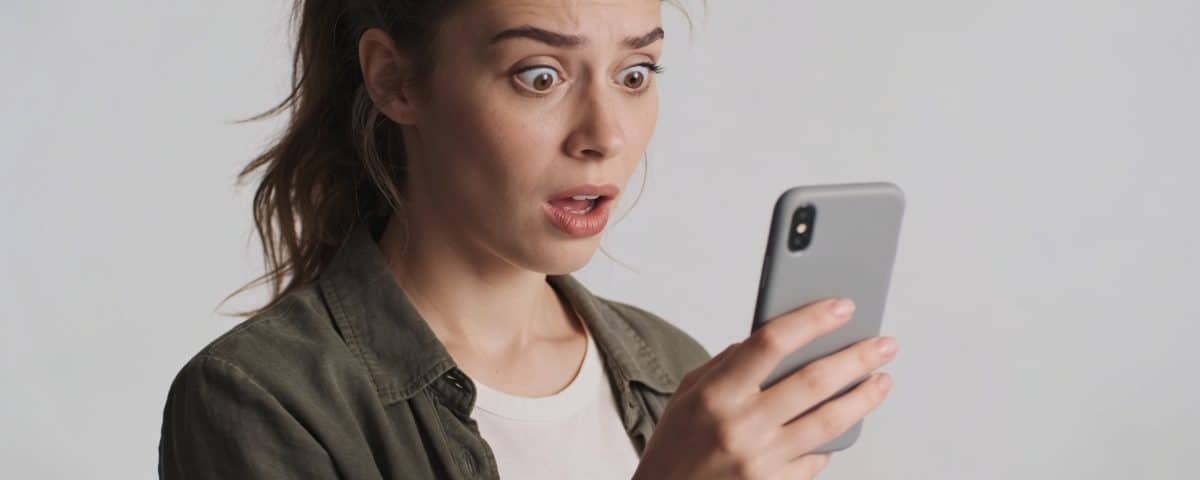 Femme surprise telephone en main regarde appel inconnu