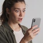 Femme surprise telephone en main regarde appel inconnu