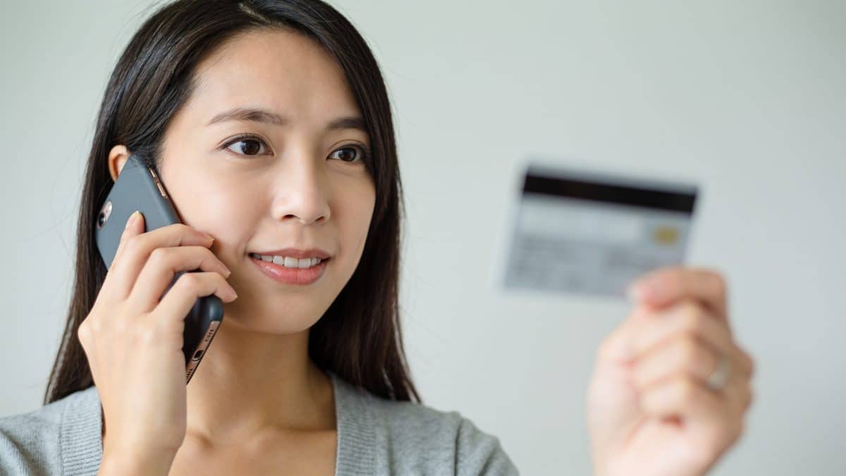 Femme au telephone tenant carte bancaire floutee