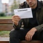Homme assis sur un banc tenant une lettre de licenciement