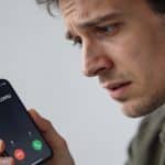 Homme inquiet regarde son smartphone affichant appel inconnu