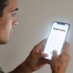 Homme regarde ecran de smartphone affichant numero inconnu