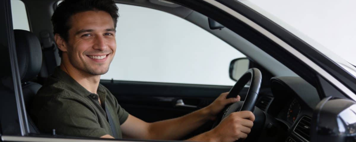 Homme souriant au volant dune berline noire