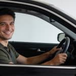 Homme souriant au volant dune berline noire