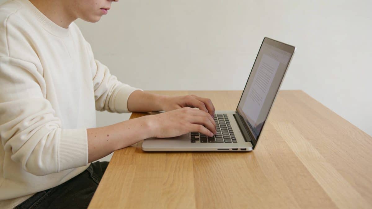Jeune adulte ecrivant un projet sur ordinateur