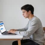 jeune adulte assis devant ordinateur consultant offres demploi