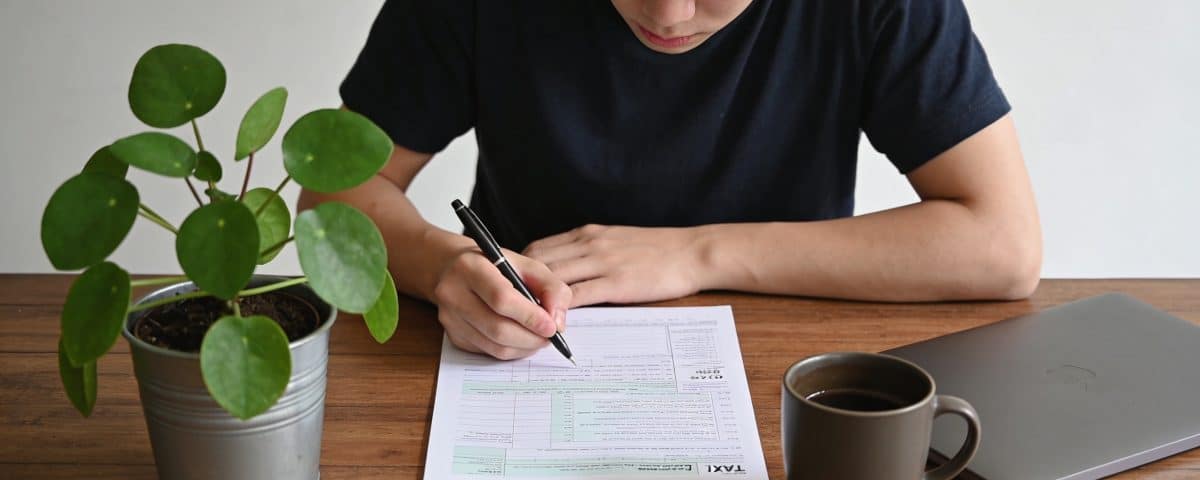 Jeune adulte assis bureau remplissant formulaire fiscal