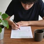 Jeune adulte assis bureau remplissant formulaire fiscal