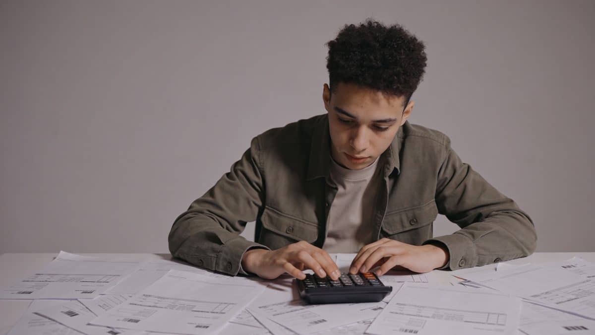 Jeune entrepreneur calcule des couts sur bureau encombre de factures