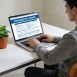 Jeune homme assis devant ordinateur consultant allocation chomage