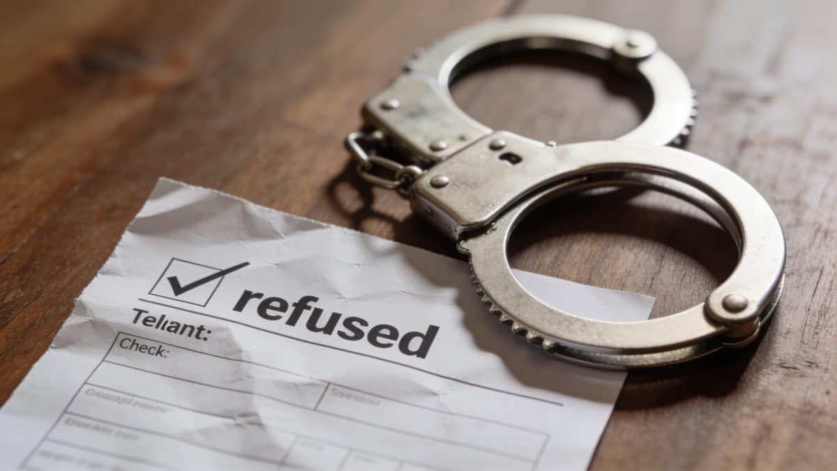 Juge tenant cheque refuse, menottes posees sur table