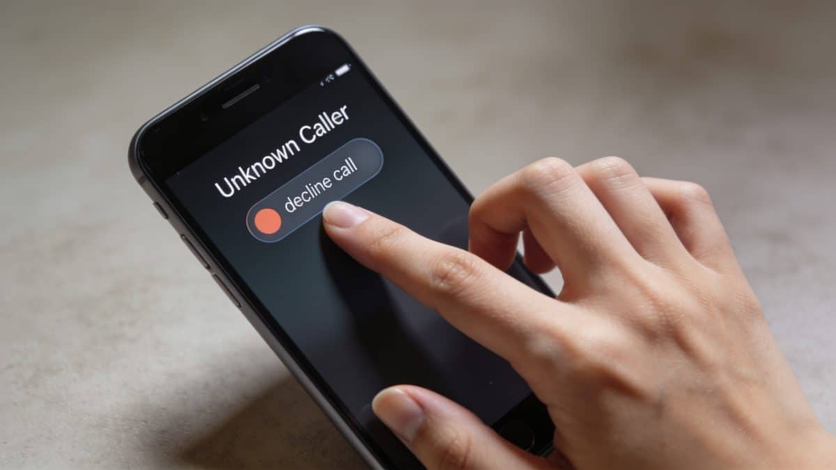 Main de femme bloquant un appel inconnu sur smartphone