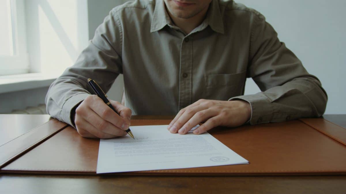Main tenant signe lettre officielle sur bureau