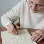 Main vieillissante ecrivant un document juridique manuscrit