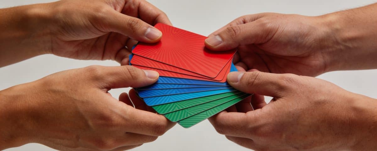 Plusieurs mains empilent des cartes cadeaux colorées