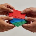 Plusieurs mains empilent des cartes cadeaux colorées