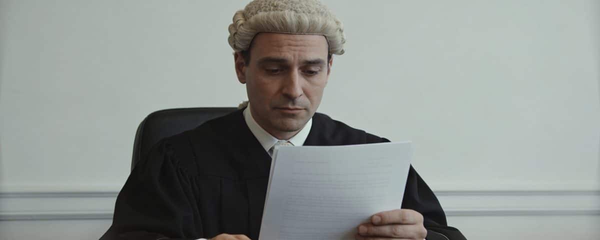 Notaire assis derriere bureau bois lisant document