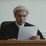 Notaire assis derriere bureau bois lisant document