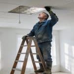 ouvrier inspectant plafond isole dans appartement lumineux