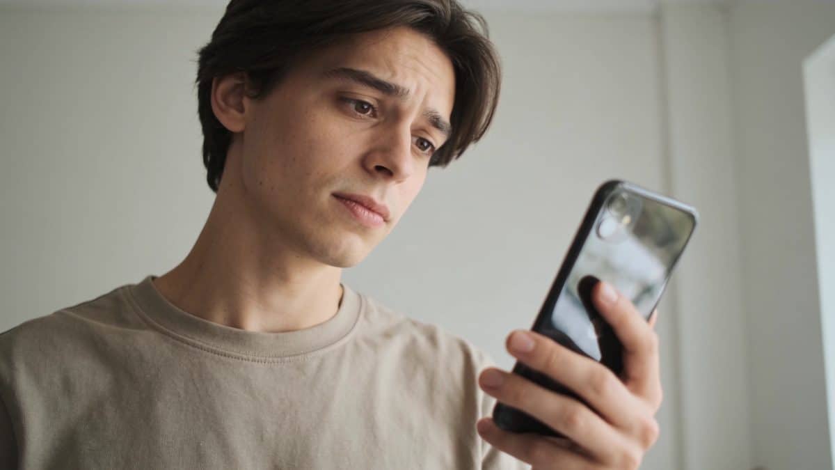 Personne hesitante regardant ecran de smartphone inconnu