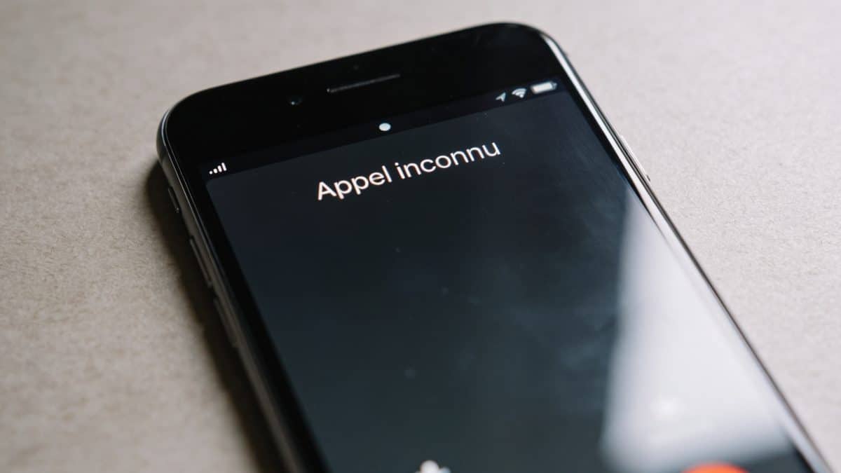 Personne regarde ecran smartphone affichant appel inconnu