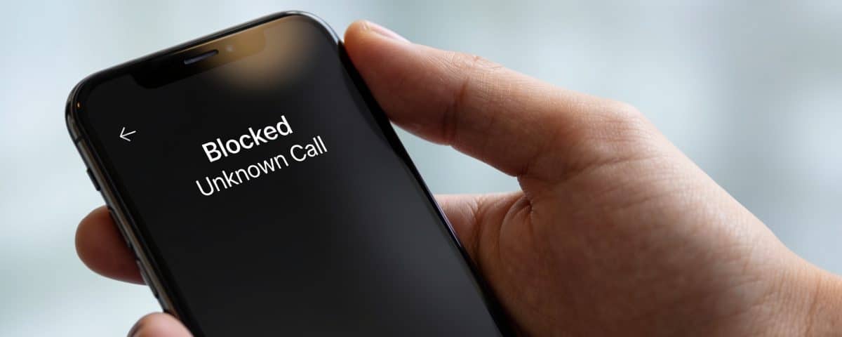 Smartphone en main affichant un appel inconnu bloqué