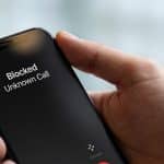 Smartphone en main affichant un appel inconnu bloqué