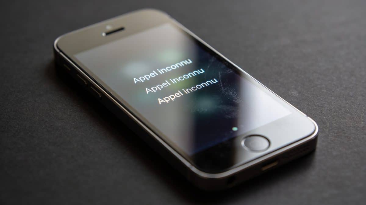 Smartphone affichant appel inconnu repetitif sur fond sombre