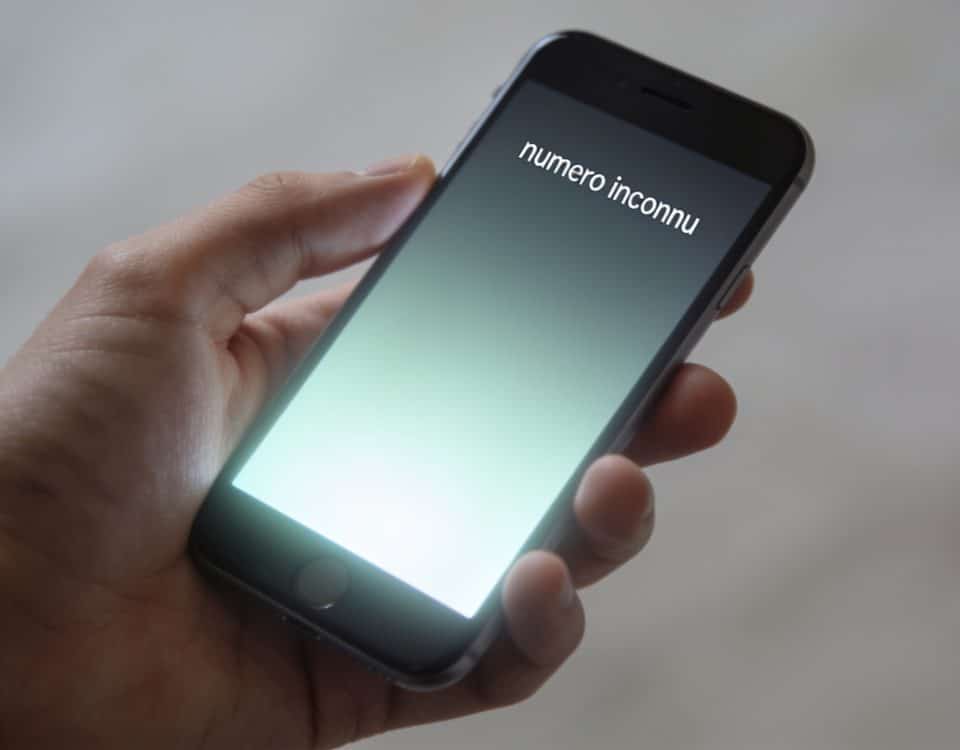 smartphone en main affichant numero inconnu ecran lumineux