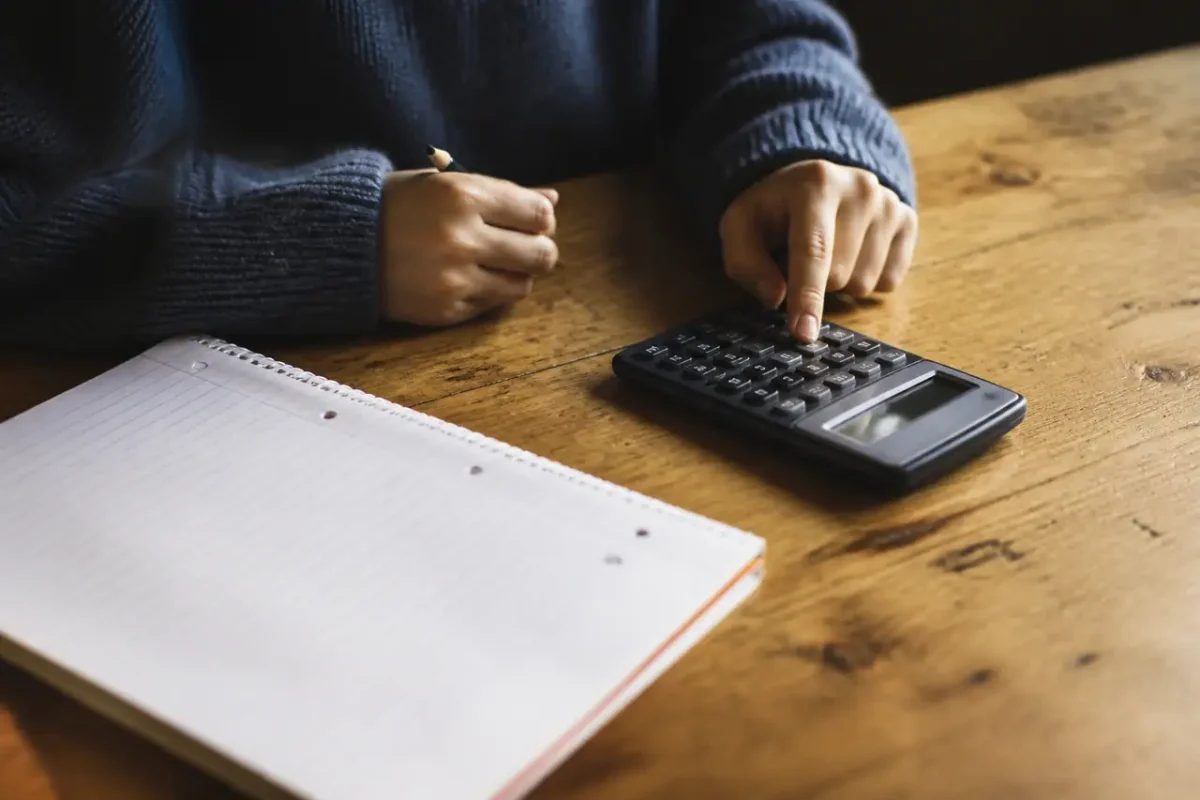 Addition et calculatrice posees sur une table en bois