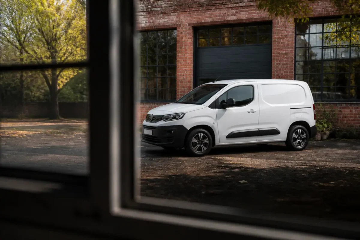 Camionnette electrique blanche garee devant un atelier en briques