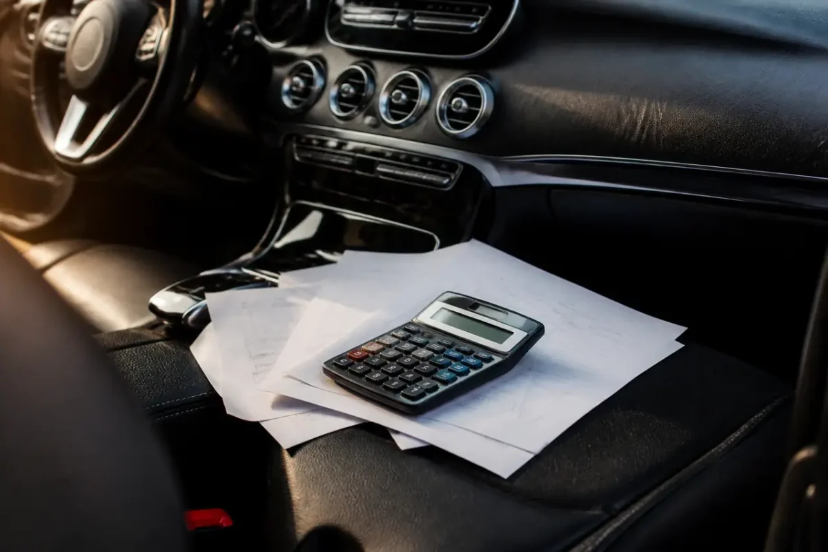 Chauffeur devant tableau de bord avec factures et calculatrice