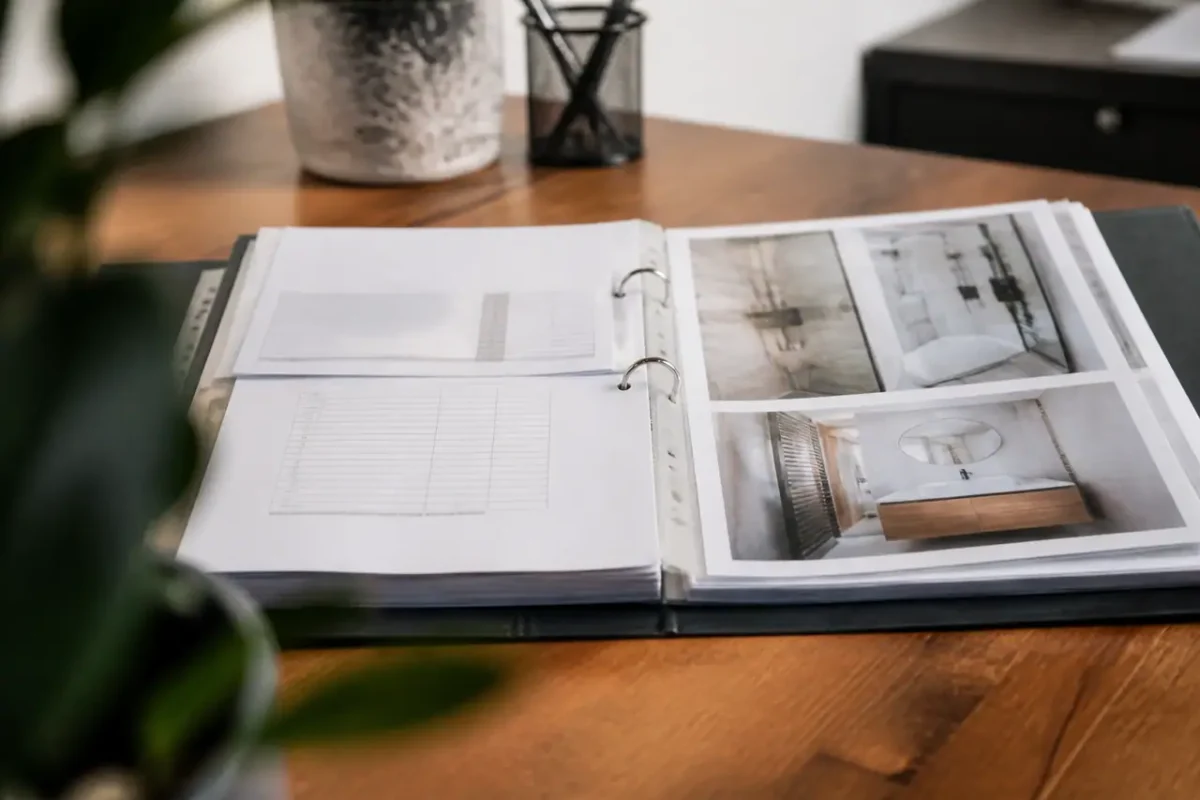 Classeur ouvert avec devis, facture et photos sur bureau