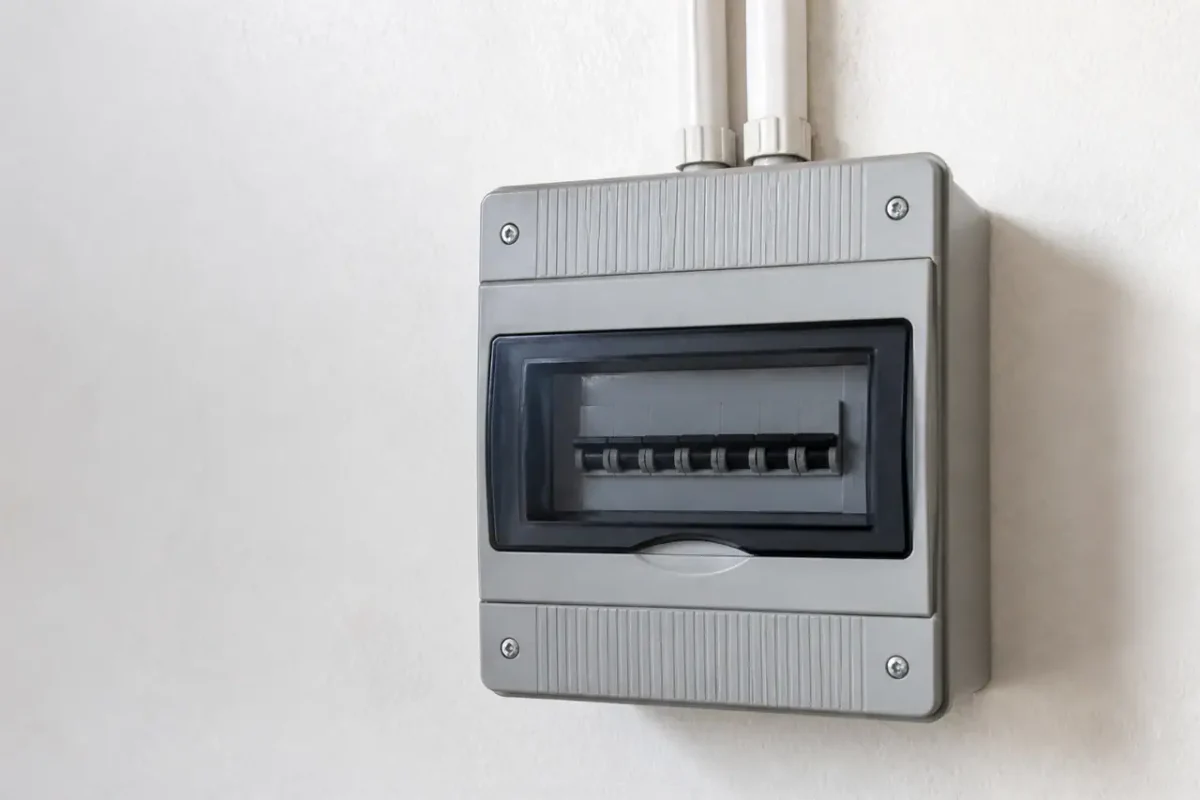 Compteur electrique gris fixe sur un mur blanc