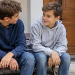 Deux freres assis sur un banc devant une maison