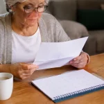 Femme agee assise lisant une lettre pres du calendrier