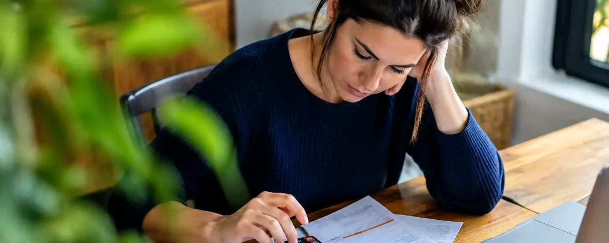 Femme assise devant bulletin de paie et calculatrice