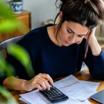 Femme assise devant bulletin de paie et calculatrice