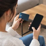 Femme assise tenant une carte bancaire devant un telephone