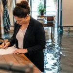 Gerant debout dans boutique inondee remplissant formulaire papier