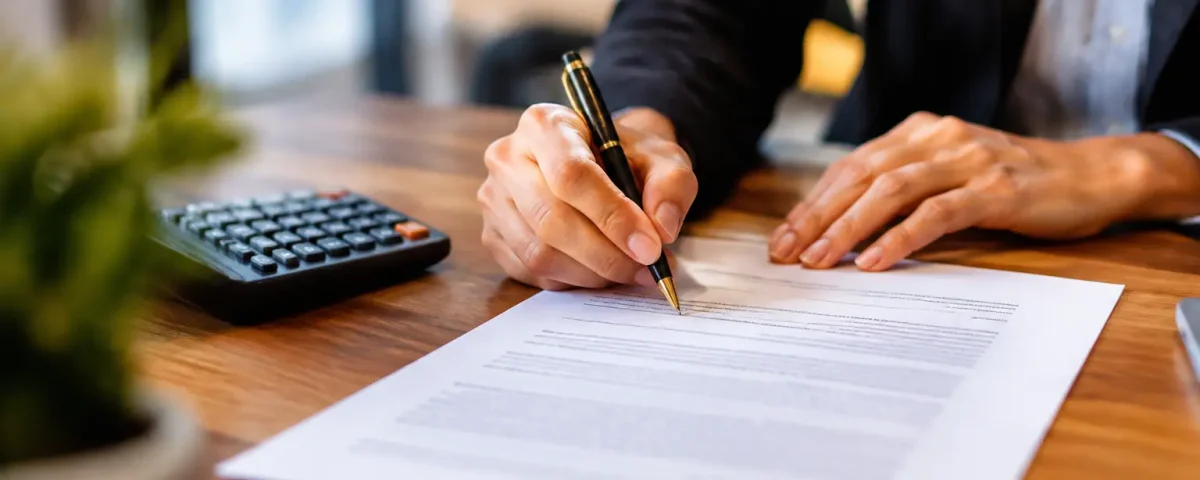 Main signant un contrat papier pres dune calculatrice