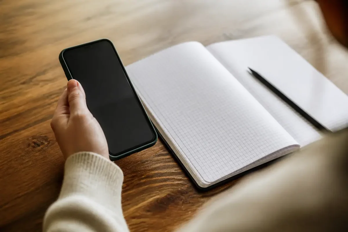 Une main tient un smartphone pres du cahier ouvert