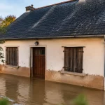 Maison basse cernee par eau brune, portes fermees