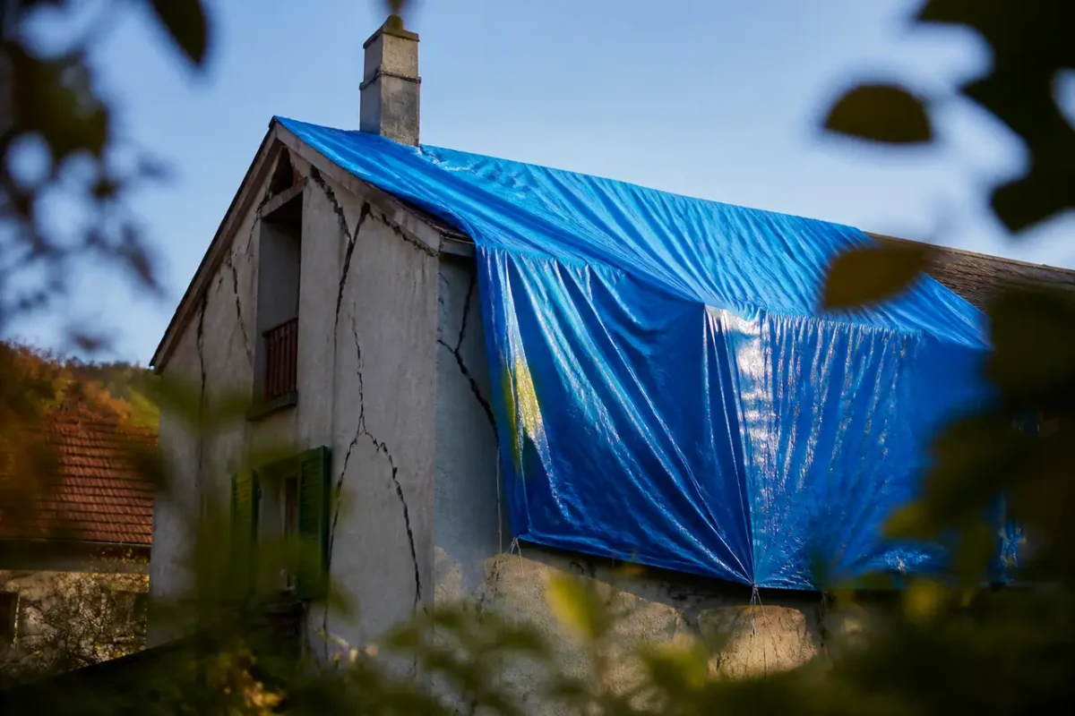 Maison fissuree couverte par une bache bleue